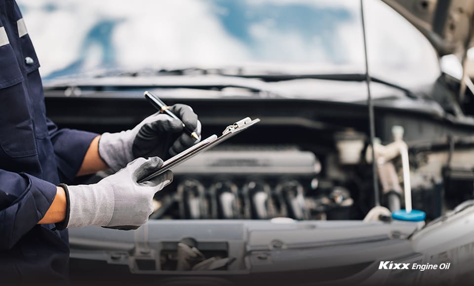 A mechanic inspecting the engine and checking the engine oil specs for the vehicle