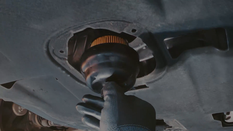 A gloved hand inserting a oil filter