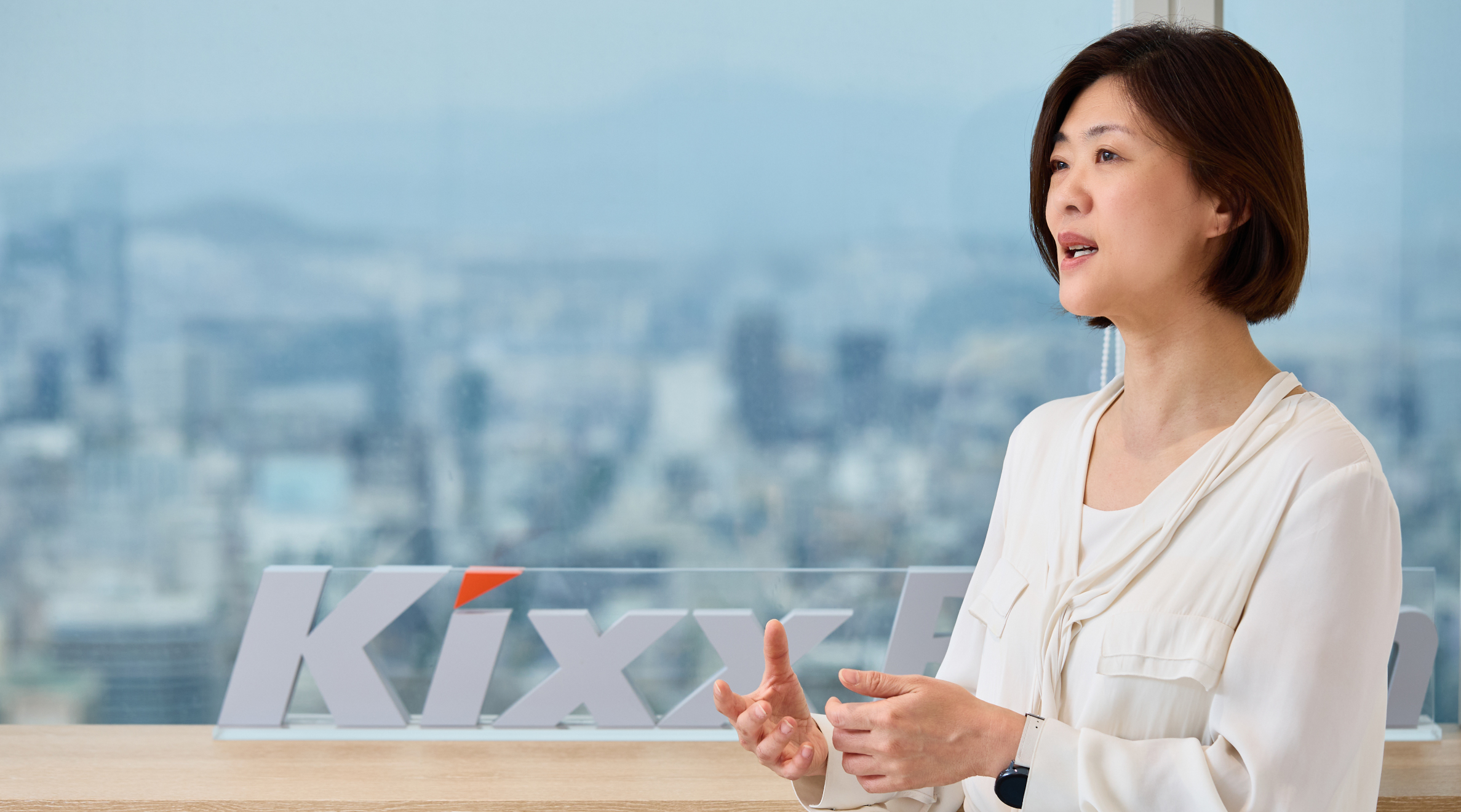 Team Leader Ji Seon Park stands near a white Kixx logo 