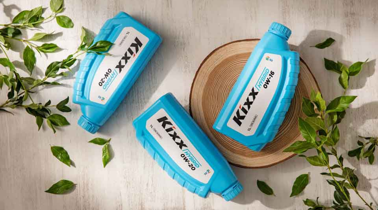 Kixx HYBRID engine oil on top of a wooden stump with green foliage 