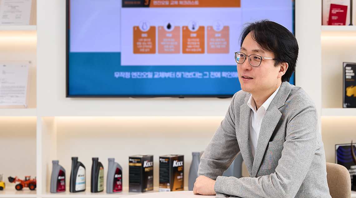 Changbeom Lee sits in a room filled with Kixx products and a TV 