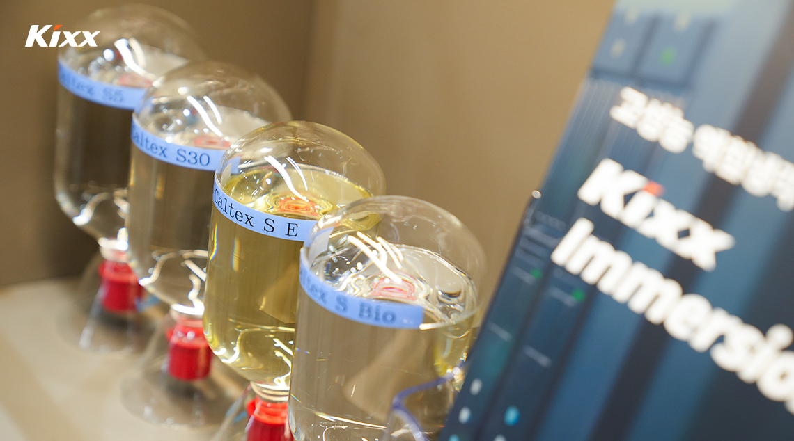 Glass containers filled with Kixx immersion cooling fluids displayed at exhibition booth.