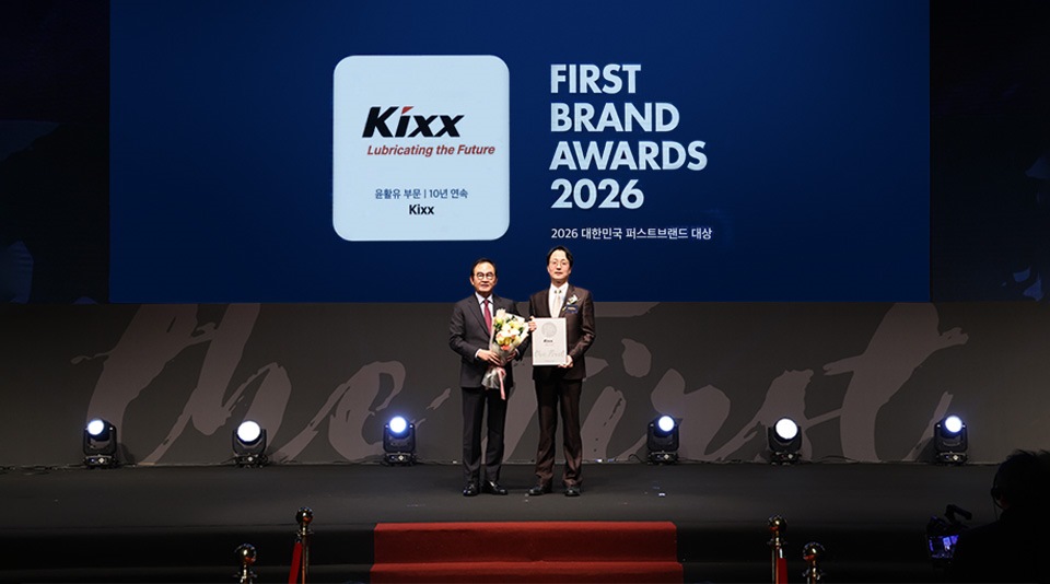 Two executives holding an award certificate on stage at the First Brand Awards 2026 ceremony, with a large screen displaying the Kixx logo and the text ‘First Brand Awards 2026,’ celebrating Kixx as the No.1 lubricants brand for 10 consecutive years.